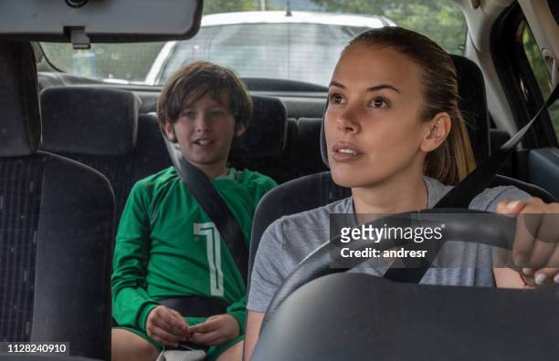 happy soccer mom transporting kid to football practice in her car - soccer mom stock pictures, royalty-free photos & images