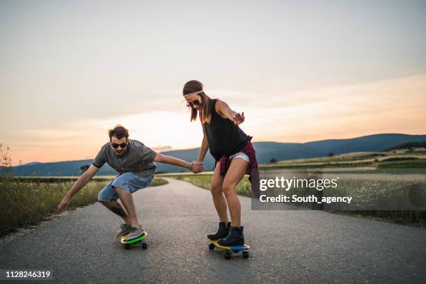 junges paar reiten skateboards zusammen - longboard skating stock-fotos und bilder