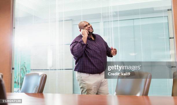 afrikanisch-amerikanischer geschäftsmann mit großen bauen auf handy - chubby men stock-fotos und bilder