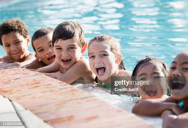 multi-ethnic group of children on side of swimming pool - boy-with-a-girl-playing-at-the-poolside stock pictures, royalty-free photos & images