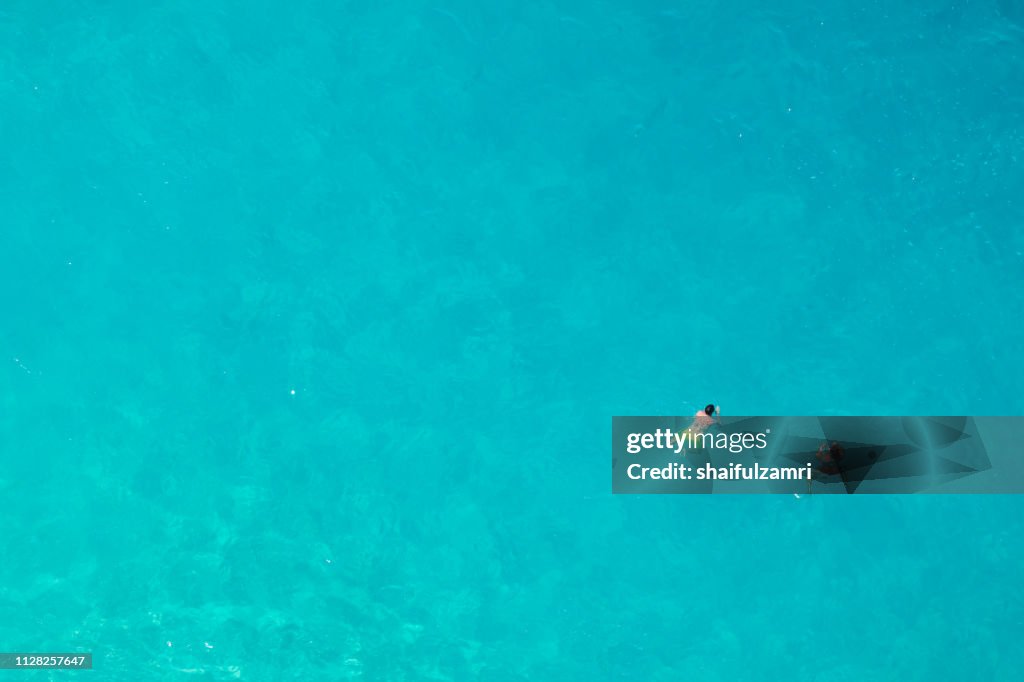 Aerial view of people swimming in the transparent turquoise sea.