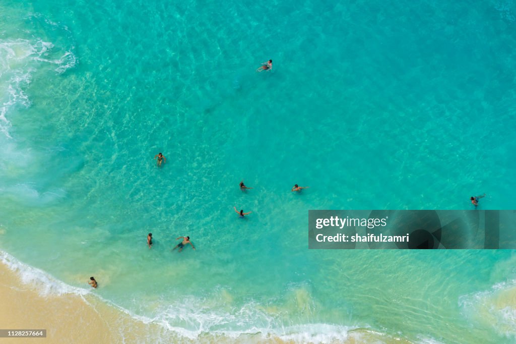 Aerial view of people swimming in the transparent turquoise sea.