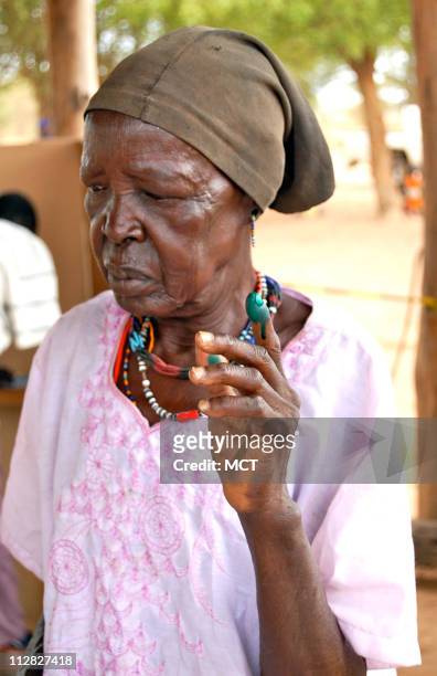An elderly, first-time woman voter outside Terekeka, southern Sudan, holds up her inked finger, designed to ensure that nobody voted twice during...