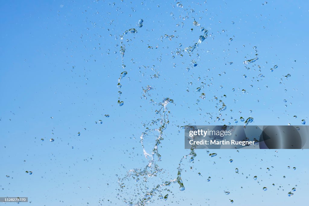 Splash of water (drops of water) against clear blue sky. Bavaria, Germany.