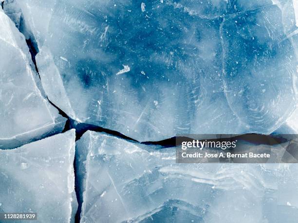 full frame of the textures formed of a block of cracked ice on a blue color background. - glatte oberfläche stock-fotos und bilder