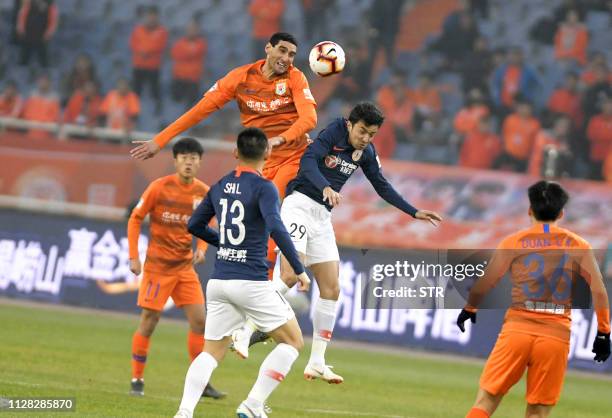 Marouane Fellaini of Shandong Luneng heads the ball next to Nizamdin Ependi of Beijing Renhe during the Chinese Super League football match between...