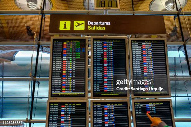 hand signaling a departure board at madrid barajas airport t4 terminal - madrid airport stock pictures, royalty-free photos & images