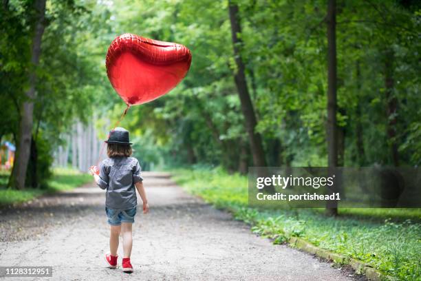 boy with heart shape balloon - heart balloon stock pictures, royalty-free photos & images