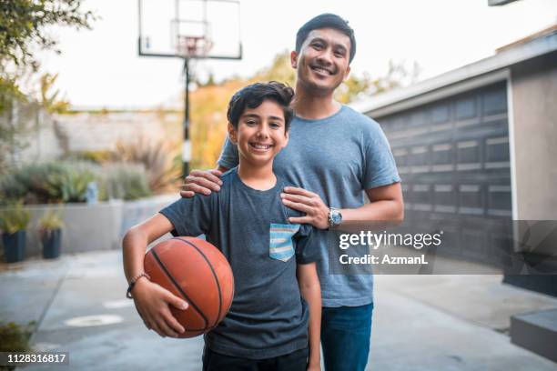 gelukkige jongen en vader permanent op het basketbalveld - basketball portrait stockfoto's en -beelden