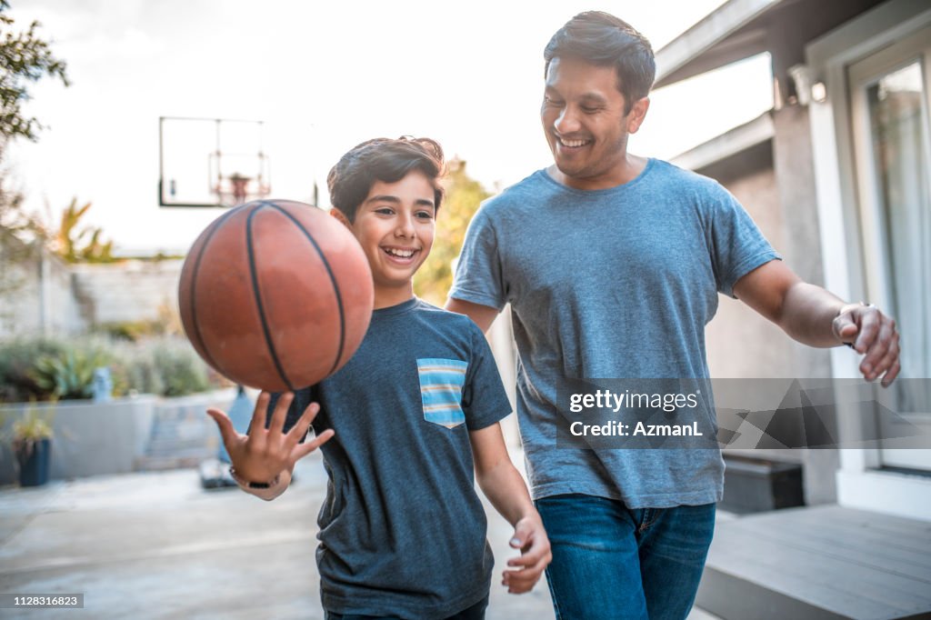 Junge Spinnen Basketball während des Gehens von Vater