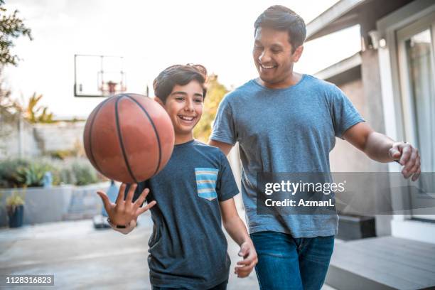 niño girando baloncesto mientras camina por el padre - kids fitness fotografías e imágenes de stock