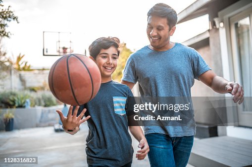 Boy spinning basketball while walking by father Boy spinning basketball while walking by father