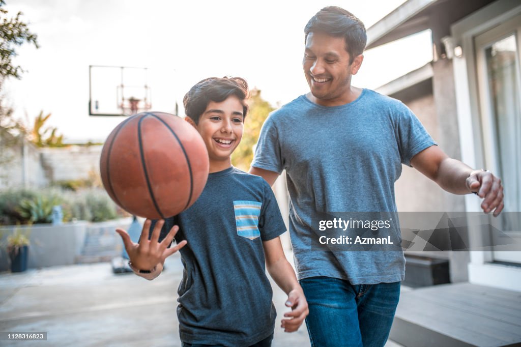 Boy spinning basketball while walking by father
