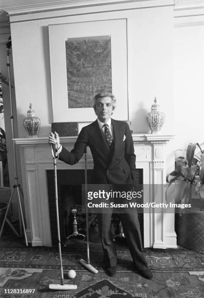 Portrait of American fashion designer Ralph Lauren as he poses, with pair of polo mallets, in front of a fireplace in his office , New York New York,...