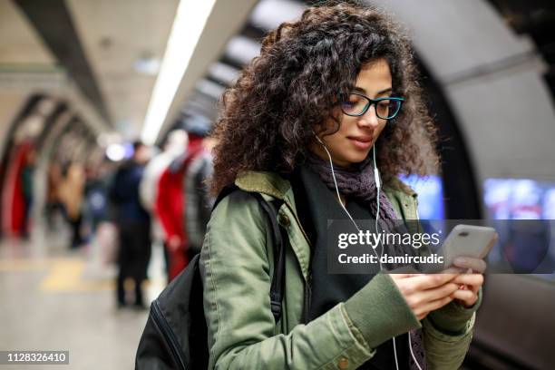 young woman using mobile phone in the subway station - underground station stock pictures, royalty-free photos & images