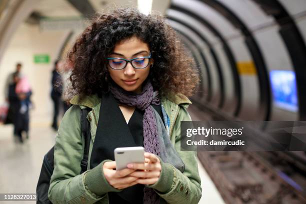 young female commuter using mobile phone in the subway station - girl waiting stock pictures, royalty-free photos & images