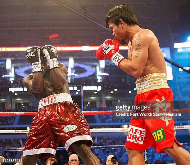 Joshua Clottey covers up as Manny Pacquiao closes in during the main event, the 12-round WBO World Welterweight title bout, at Cowboys Stadium in...