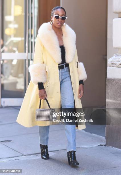 Guest is seen wearing a fur trimmed coat, blue jeans, black boots and checkered bag outside the Jason Wu show during New York Fashion Week:...