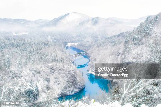 tadami line train across tadami river on first bridge in winter, fukushima, japan - río del este fotografías e imágenes de stock