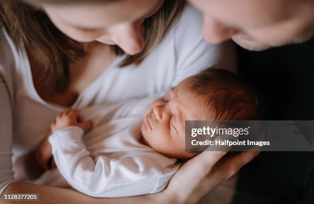 a close-up of a mother and father holding a newborn baby son at home. - nouveau né photos et images de collection