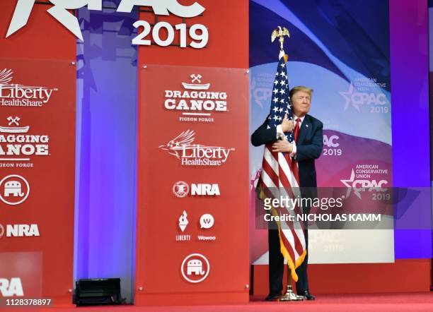 President Donald Trump hugs the US flag as he arrives to speak at the annual Conservative Political Action Conference in National Harbor, Maryland,...