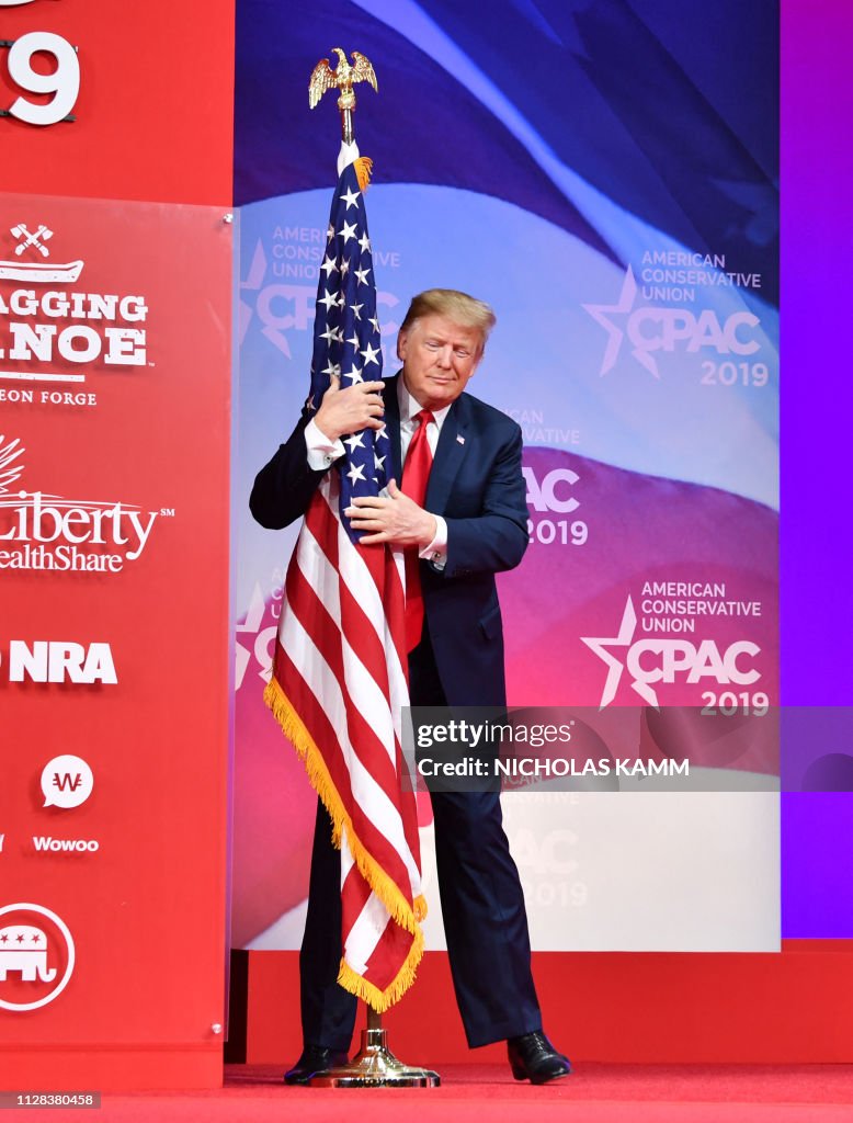 US President Donald Trump hugs the US flag as he arrives to speak at ...
