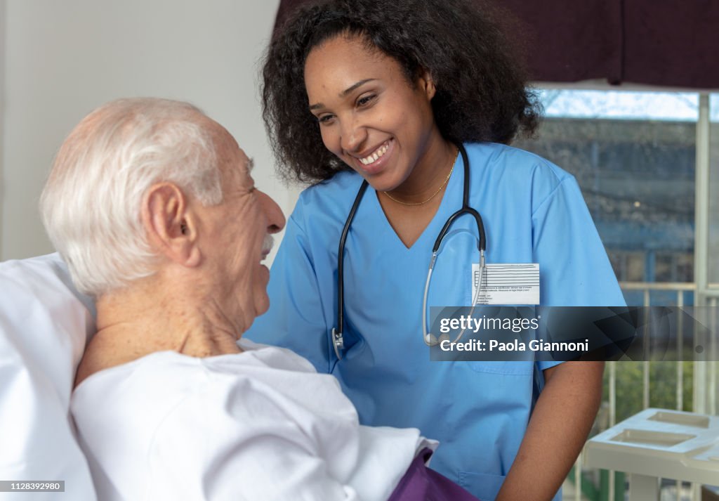 Enfermeira, sorrindo para o paciente deitado na cama