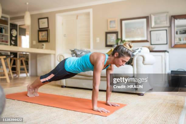 frau in plank pose auf der matte zu hause üben - push ups stock-fotos und bilder