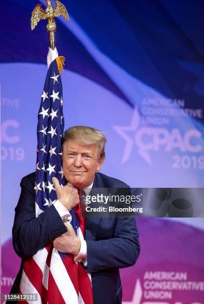 President Donald Trump hugs an American flag before speaking during the Conservative Political Action Conference in National Harbor, Maryland, U.S.,...