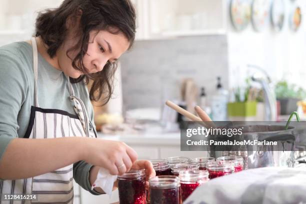 conservas conservas, étnico mezclado adolescente chica limpiando llantas de tarros de mermelada - frasco para conservas fotografías e imágenes de stock