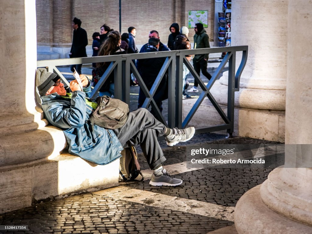 A senior man rests under the Bernini’s colonnade in St. Peter’s square