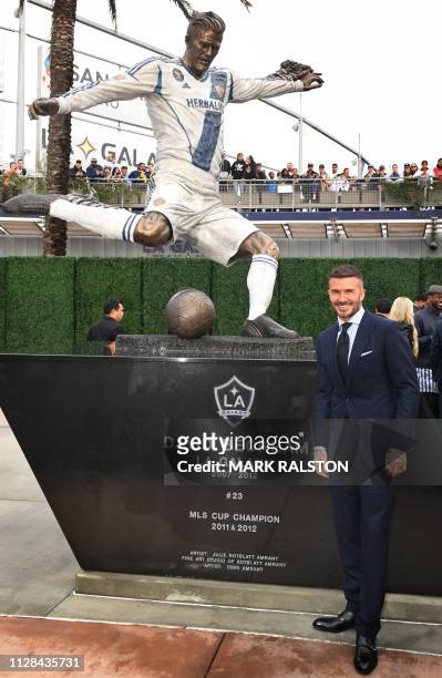 Former Los Angeles Galaxy midfielder David Beckham poses beside his newly unveiled statue at the Legends Plaza in Carson, California on March 2,...