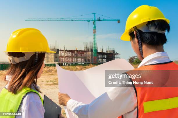 female architect or engineer with blueprint at building construction site, teamwork discussion,or job occupation concept - civil engineering stock pictures, royalty-free photos & images