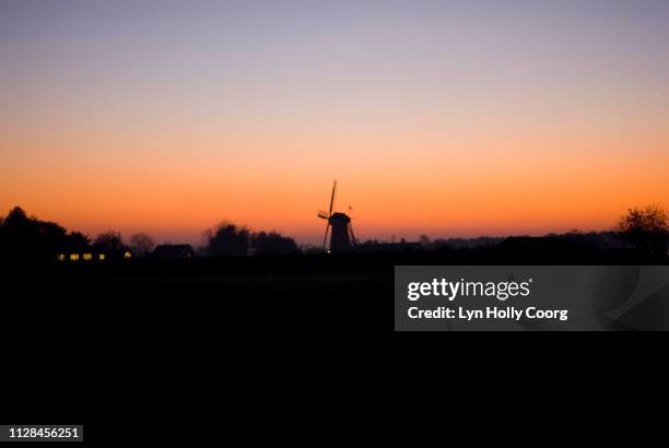 dutch windmill silhouetted against horizon at sunset - lyn holly coorg stockfoto's en -beelden