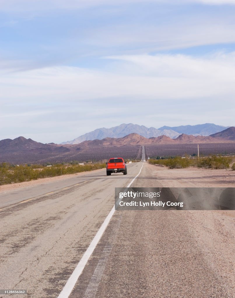 Long straight highway in Mojave Desert California USA with red truck