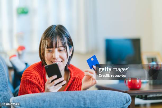 young woman shopping online at home - content japanese ethnicity stock pictures, royalty-free photos & images