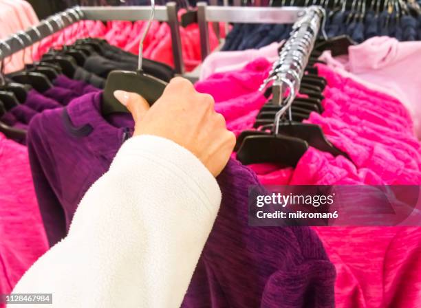 woman's hands selecting cloths in fashion store - sportswear shopping stockfoto's en -beelden