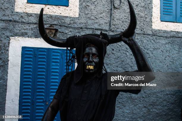Man with his face covered in oil and soot and carrying bull horns representing a devil during a traditional carnival festival. Every year Luzon hosts...