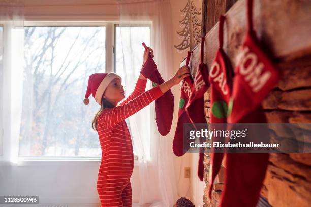 girl hanging christmas stockings on a fireplace - stockings stock pictures, royalty-free photos & images
