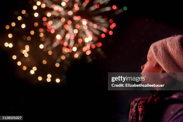 rear view of a boy watching a firework display - firework display stock-fotos und bilder