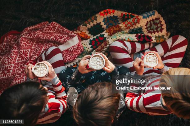 three children sitting on a couch drinking hot chocolate - family on couch with mugs stock pictures, royalty-free photos & images