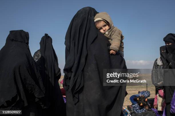 Civilians who have fled fighting in Bagouz wait to board trucks after being screened by members of the Syrian Democratic Forces at a makeshift...