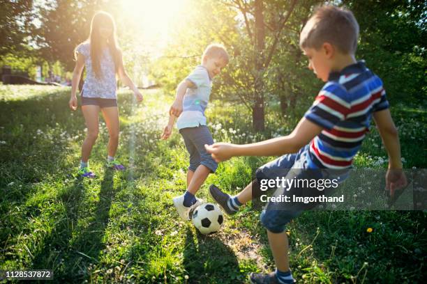 kinder spaß fußballspielen im park - backyard football stock-fotos und bilder