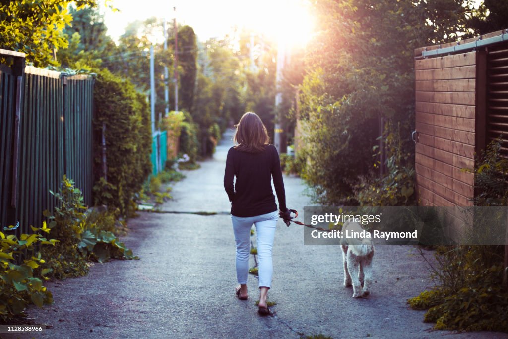 A woman walking with her dog in an alley