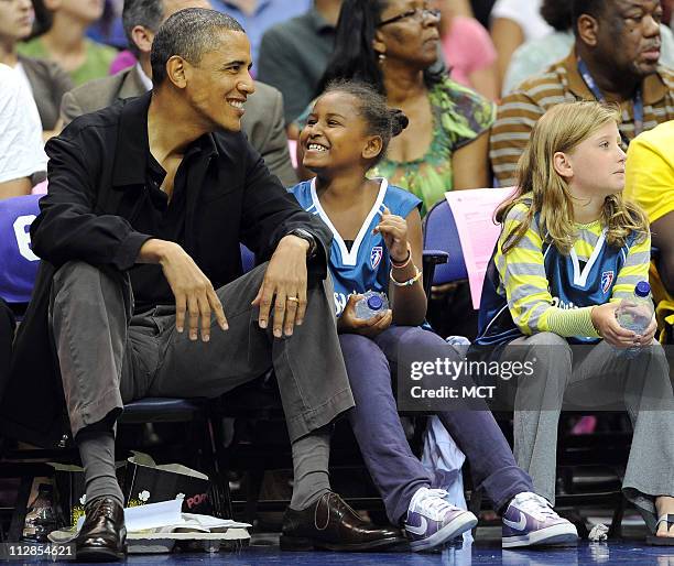 President Barack Obama and his daughter, Sasha, enjoy a chuckle while watching the time-out entertainment on the floor during the game between the...