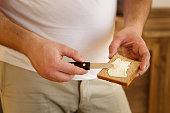 overweight man spreading mayonnaise on bread