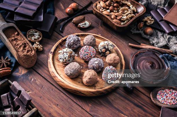 chocolade truffels en diverse donkere chocolade met noten op rustieke oude keukentafel - chocolate powder stockfoto's en -beelden