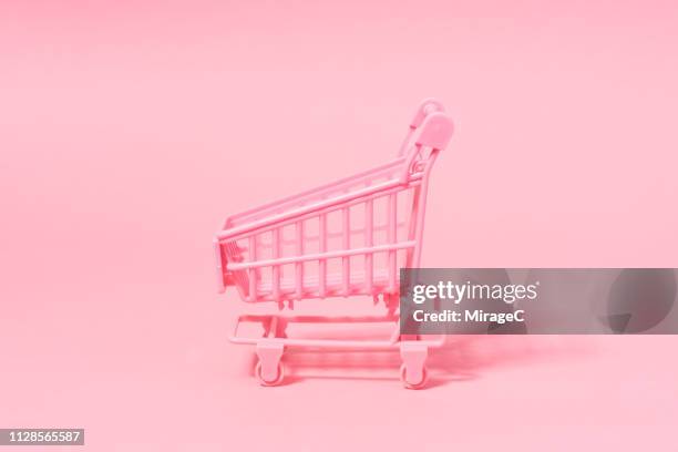 pink shopping cart on pink - shopping trolleys stockfoto's en -beelden