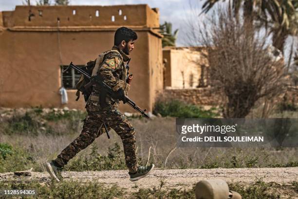 Member of the Syrian Democratic Forces runs for cover during shelling on the Islamic State group's last holdout of Baghouz, in the eastern Syrian...