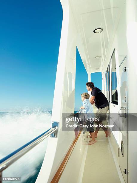 father and son looking out from yacht - family yacht stock pictures, royalty-free photos & images